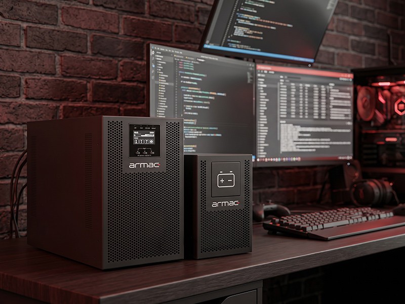 Armac UPS and battery module on a desk next to a computer workstation.